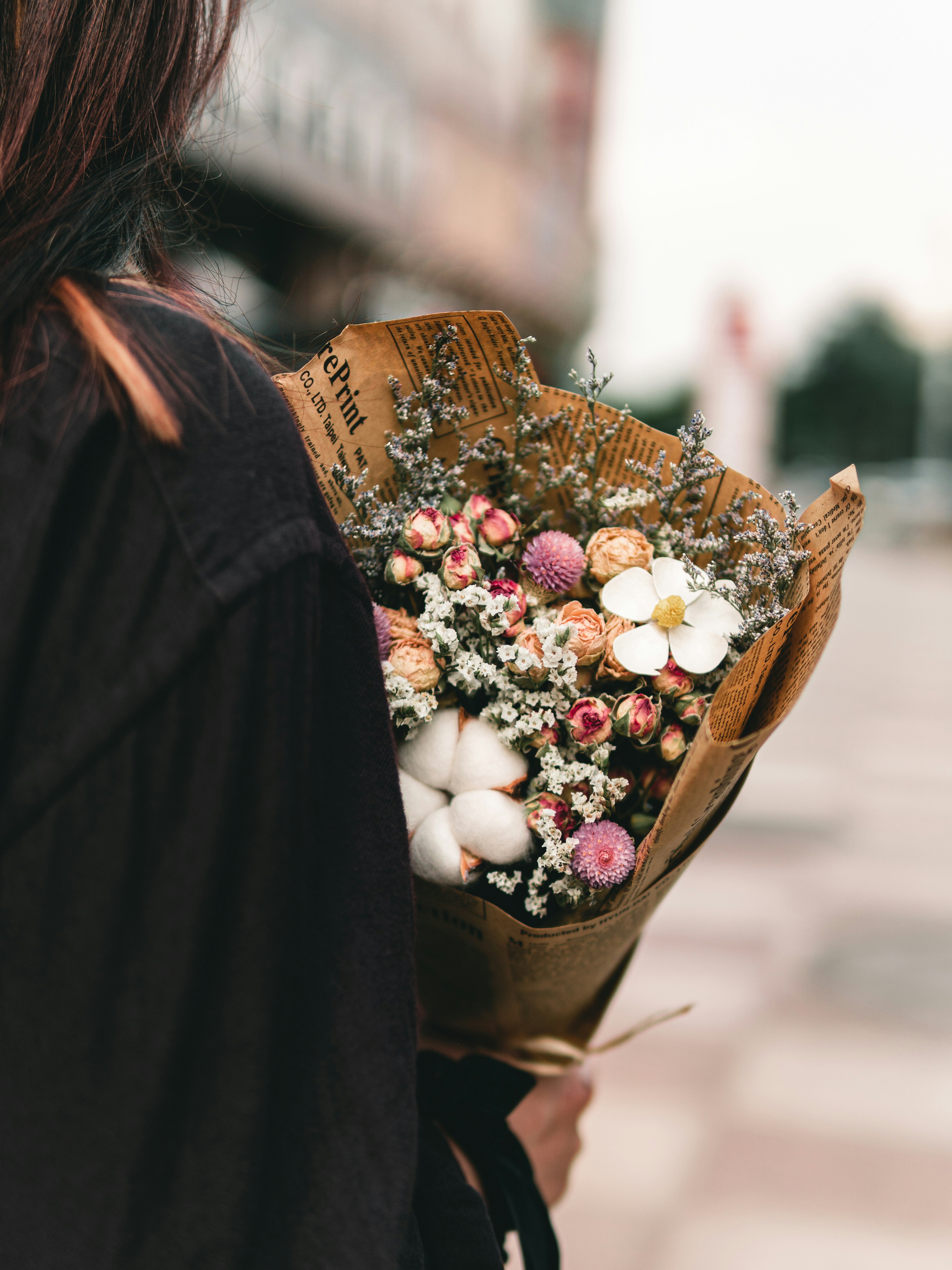 woman in black coat holding brown basket with white and red round fruits